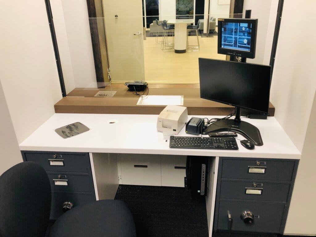 Teller desk with a quad-split camera feed monitor overlooking the branch lobby