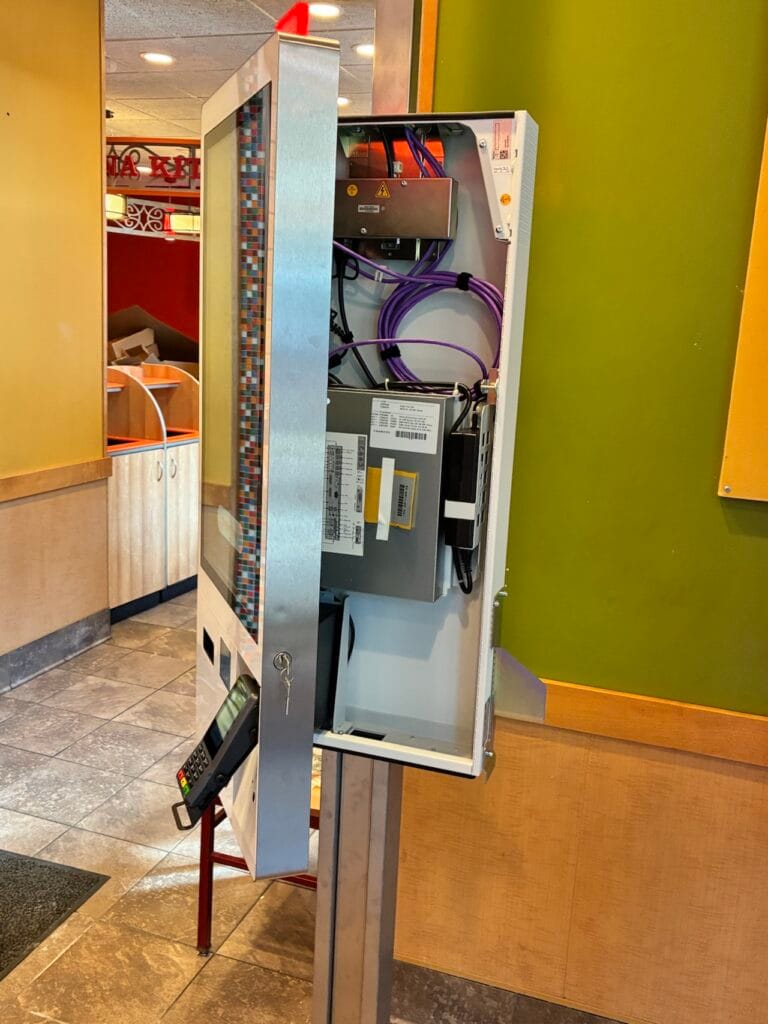Open kiosk service panel showing internal wiring and power supply