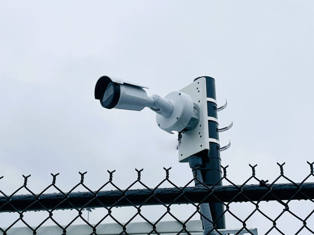 Bullet camera on a bracket above a chain-link perimeter fence